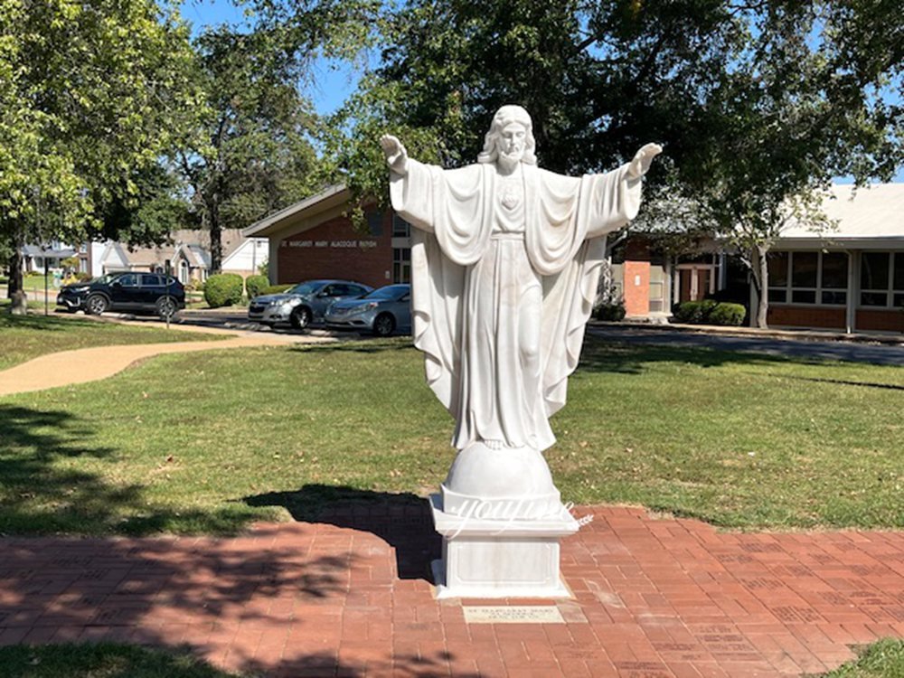 A sculpture of Jesus with outstretched arms in a community