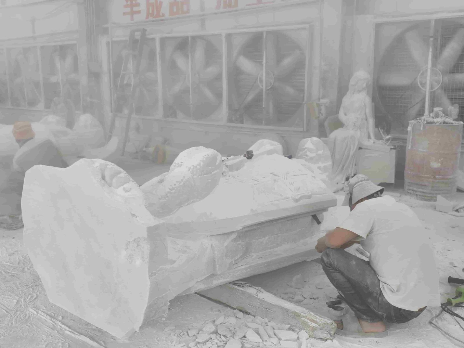 Large Saint Michael statue carving process and details 06 — carver wearing a mask hand-refining the lying Saint Michael blank