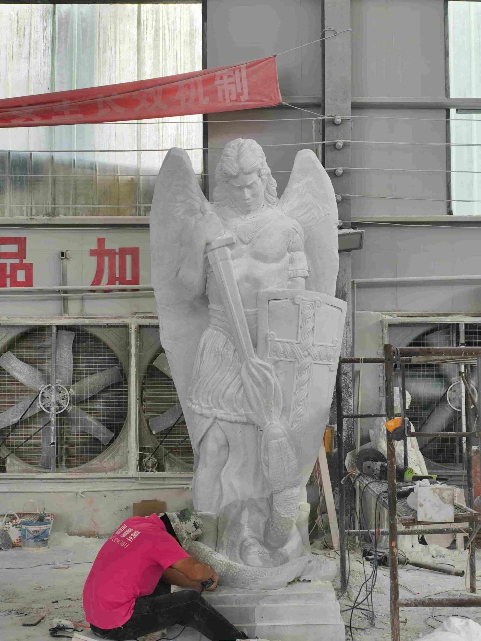 Large Saint Michael statue carving process and details 08 — statue raised upright and strapped for safe detailing