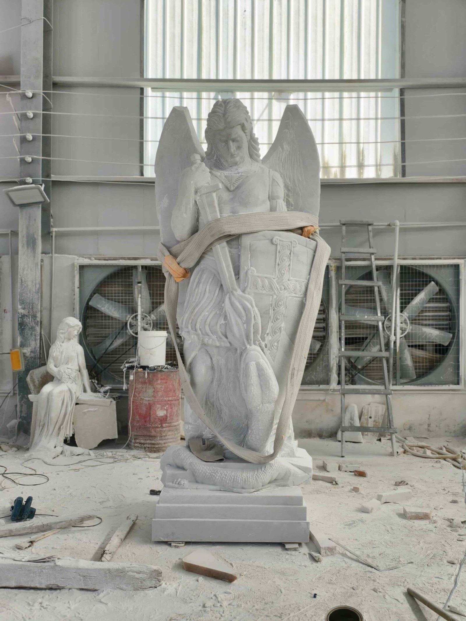 Large Saint Michael statue carving process and details 09 — carver hand-finishing the foot and serpent scales at the plinth