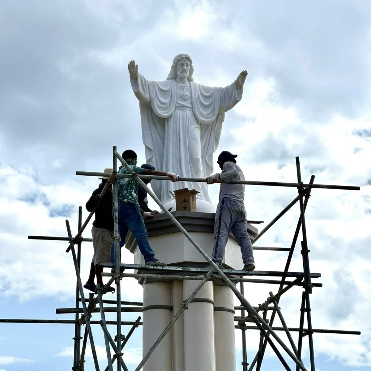 Installation of a large marble Jesus statue on a pedestal