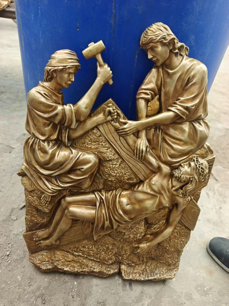 Gold-colored relief, Station XI — Jesus is nailed to the cross